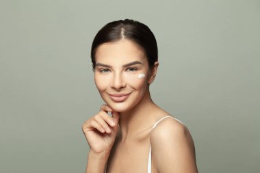 Temiz ve sağlıklı cildine nemlendirici losyon sürmüş çekici genç bir kadın. Yüz bakımı, güzellik bakımı, kozmetoloji ve kaplıca konsepti