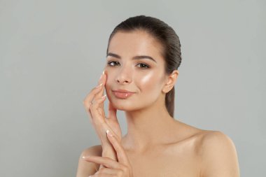 Temiz tenli güzel genç bir kadın yüzüne dokunuyor. Yüz bakımı, kozmetoloji, güzellik ve kaplıca konsepti