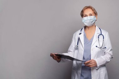 Hastane ofisinde steteskoplu beyaz önlüklü doktor kadın.