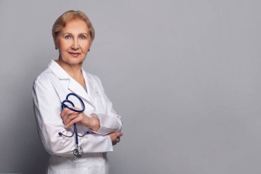 Mavi arka planda gülümseyen mutlu doktor. Steteskop tutan olgun doktor kadın.