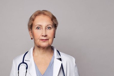 Stüdyoda gülümseyen steteskoplu bir tıp işçisi.