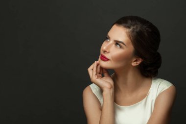 Mükemmel makyajlı zarif bir kadın siyah arka plana bakıyor.