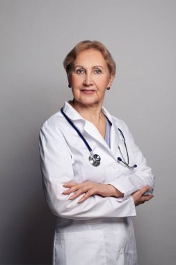 Kendine güvenen zeki doktor mavi arka planda duruyor. Olgun kadın sağlık çalışanı portresi