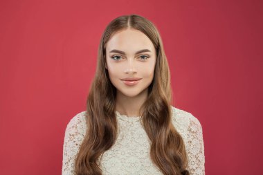 Kırmızı arkaplanda doğal makyajı olan sağlıklı genç bir kadın.