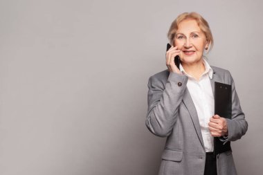 Modern akıllı telefonunu kullanarak kırışıklıkları olan kendinden emin bir iş kadınının portresi.