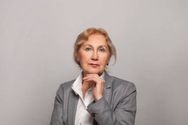 Gri arka planda gülümseyen ve kameraya bakan güzel bir son sınıf öğrencisi. Olgun kadın 60 'ların portresi