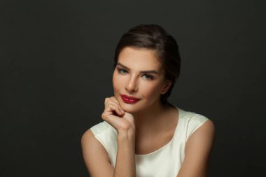 Temiz tenli, zarif saçlı ve gri arka planda şık makyajlı güzel bir kadın.