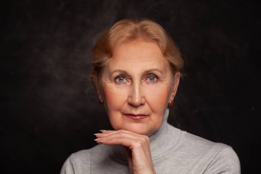 Siyah üzerine güzel, 60 yaşında sarışın bir kadının portresi.