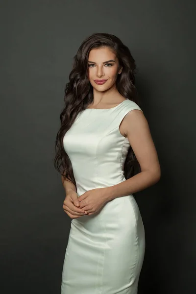 Attractive model on black background. Young woman in white dress portrait