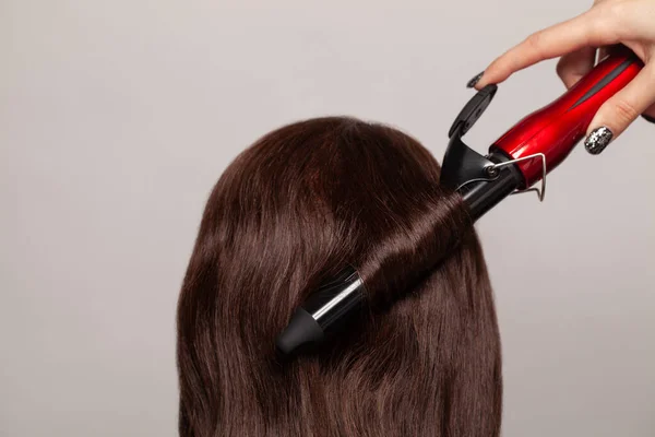 Брюнетка Зачесывающая Волосы Выпрямителем Бигуди — стоковое фото