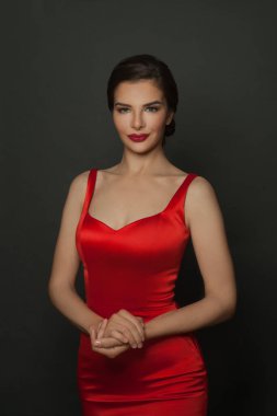 Koyu gri arka planda kırmızı elbise giyen güzel bir esmer kadın.