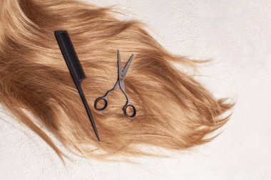 Beyaz arkaplanda kahverengi saç, tarak ve makas