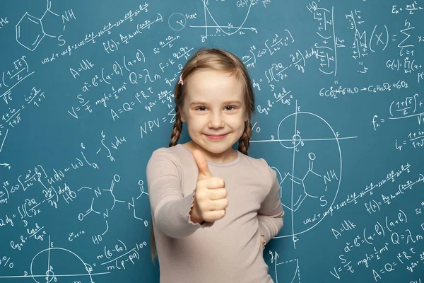 幸せなスマート子供女の子笑顔と保持親指アップ上の科学式背景 — ストック写真
