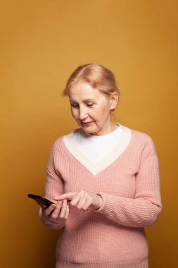 Akıllı telefon kullanan ve mesaj gönderen mutlu olgun bir kadın internet iletişiminden keyif alıyor