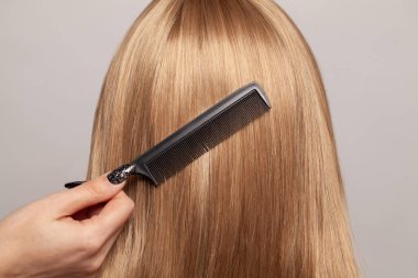 Saçlarını tarayan düz saçlı bir kadın.