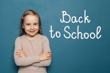 Mavi arka planda gülümseyen neşeli çocuk ve yazı okula geri dönüyor. 