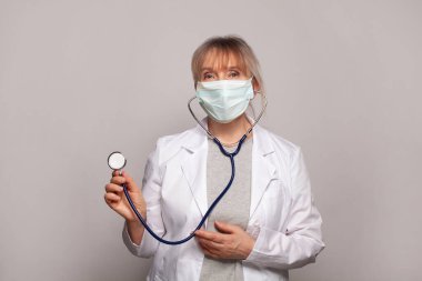 Beyaz üniformalı mutlu doktor portresi beyaz arka planda steteskopla duruyor.