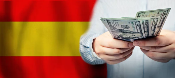 Hands holding us dollar bills on Spanish flag background. Currency exchange in Spain concept