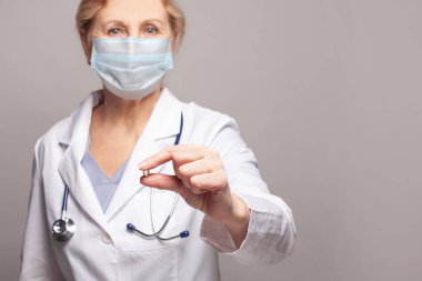 Doktor eli bir kapsülü yakın plan gösteriyor.