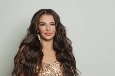 Makyajlı çekici bir kadın yüzü ve beyaz arka planda uzun dalgalı saçları var.