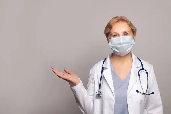Ärztin Uniform Vor Grauem Hintergrund Präsentiert Und Zeigt Mit Der — Stockfoto