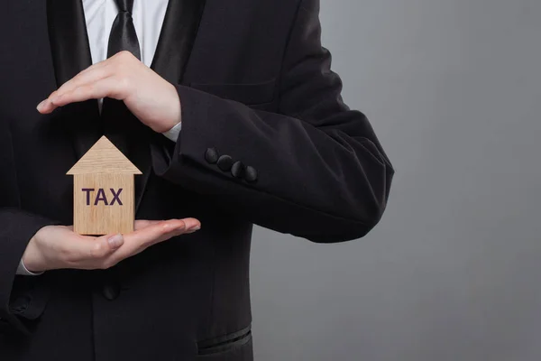 家や建物や土地の財産税の概念 税金表示付きの住宅モデルを保有するビジネスマン — ストック写真