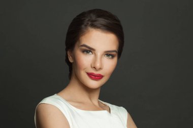 Siyah arka planda makyajlı zarif ve neşeli bir kadının yakın plan portresi.