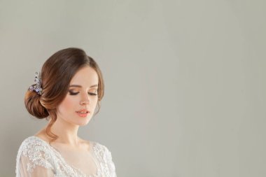 Fotokopi çekilen beyaz afiş arkaplanlı lüks dantelli bir gelinlik içinde, yeni moda makyajlı ve modaya uygun bir saç stili olan muhteşem, tatlı gelin.