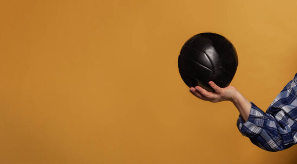 Black soccer ball on bright yellow background with copy space