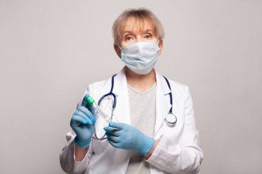 Elinde test tüpü tutan beyaz üniformalı bir sağlık görevlisi.