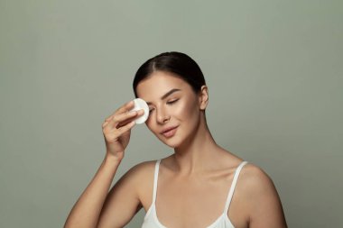 Neşeli kadın makyajını siliyor. Pamuklu güzel esmer model.