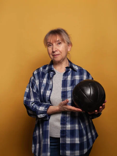 Улыбающаяся Пожилая Женщина Повседневной Жизни Держит Футбольный Мяч Желтом Фоне — стоковое фото