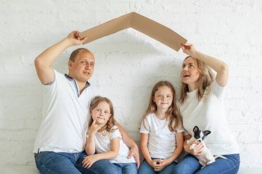 Cute family parent with children playing into new home and having fun together indoor.  Insurance, moving day house, property and investment concept