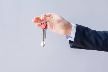 Businessman hand holding house keys on white background