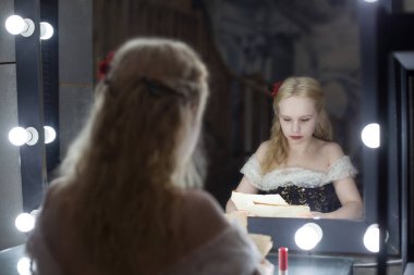 The actress or singer in the dressing room rehearses the scene sitting in front of the mirror before the performance