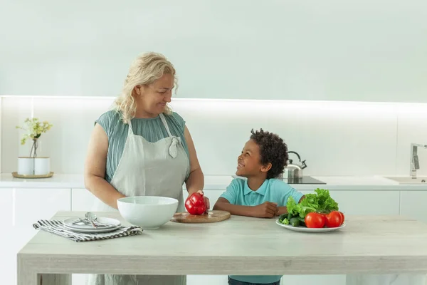 Mom with kid preparing food and chatting together in the kitchen