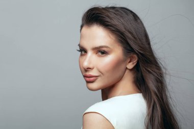 Stüdyoda gri arka planda poz veren güzel esmer kadın. Kadın saçı rüzgarı, güzel bir yüz...