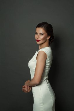 Beyaz elbiseli zarif bir kadının moda stüdyo portresi.