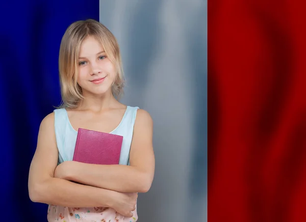 Beautiful cute little kid child girl with english book against France, French flag background. Learn France, French concept.