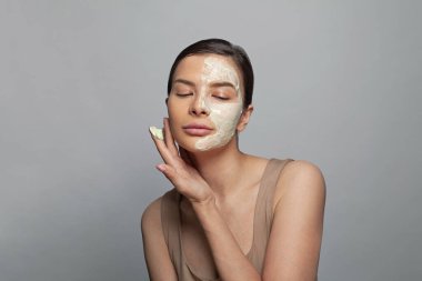 Yüzünde kozmetik maskeyle kaplıca salonunda dinlenen çekici bir kadın.