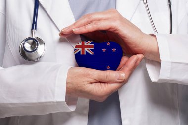 Yeni Zelandalı doktor, Yeni Zelanda kökenli bir bayrak taşıyor. Sağlık, yardım, sigorta ve tıp konsepti
