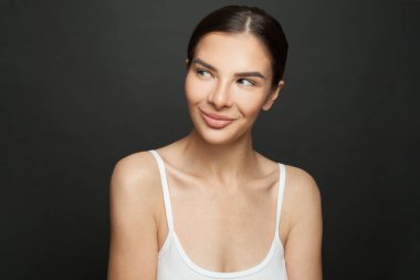 Siyah arka planda gülümseyen ve yan bakan güzel bir kadının portresi.