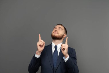 Gri arka planı işaret eden mutlu bir iş adamının portresi.