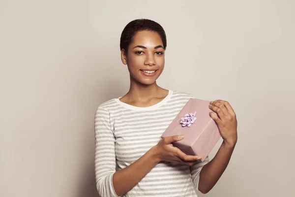 可爱的非洲裔美国年轻女子拿着白墙背景的礼品盒 带着礼物的快乐微笑模型 — 图库照片