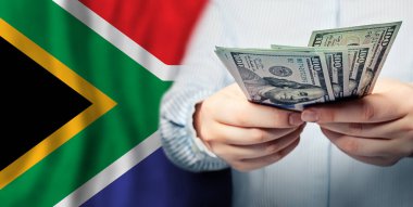 Eller Amerikan banknotunu ve Güney Afrika bayrağını tutuyor.