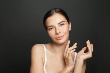 Çekici esmer kadın, mükemmel temiz tenli, siyah arka planda boş ellerini yüzünün yakınında tutan.