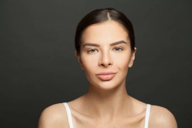 Güzel kadın model esmer, sağlıklı ve temiz tenli kadın siyah kameraya bakıyor.