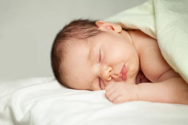 新生児は白い背景にベッドの上に横たわっている — ストック写真