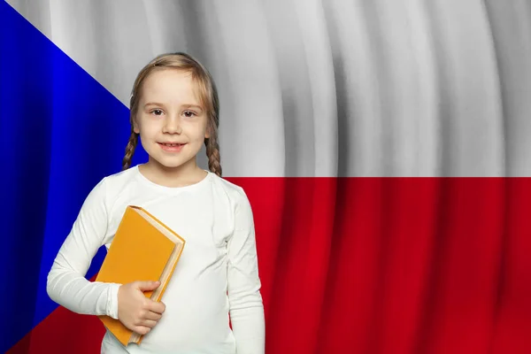 小さな女の子の子供は笑顔とチェコの国旗を背景に本を保持 チェコ共和国の教育と学校のコンセプト — ストック写真