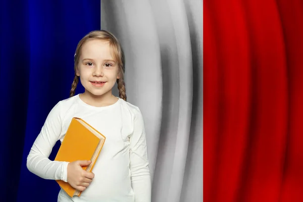 快乐的小女孩手里拿着一本法国国旗背景的书 教育和学校在法国的概念 学习法语 — 图库照片